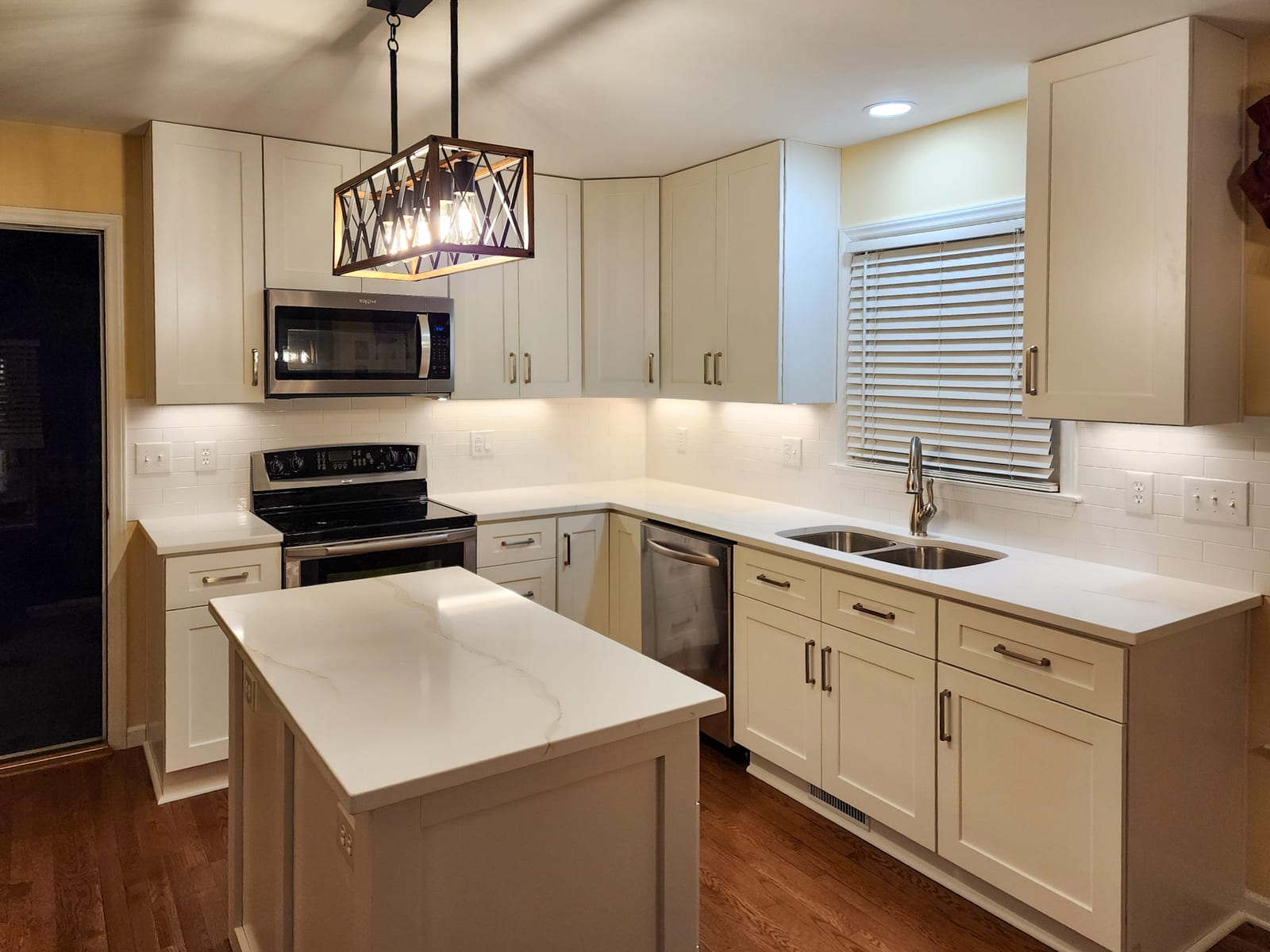 Kitchen remodel range wall with white cabinets, tile backsplash, and sink window